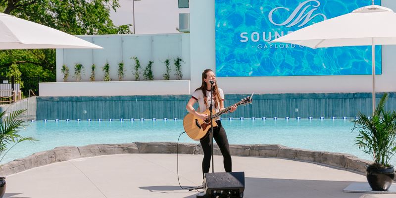 Live acoustic guitar player and singer in front of SoundWaves pool at screen Live acoustic guitar player and singer in front of SoundWaves pool at screen